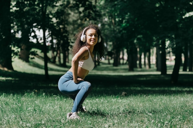 Mulher jovem sorridente fazendo exercícios matinais no parque