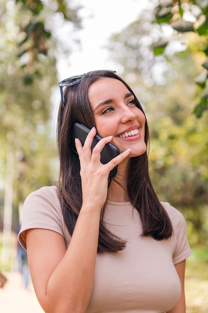 Mulher jovem sorridente ligando por telefone em um parque