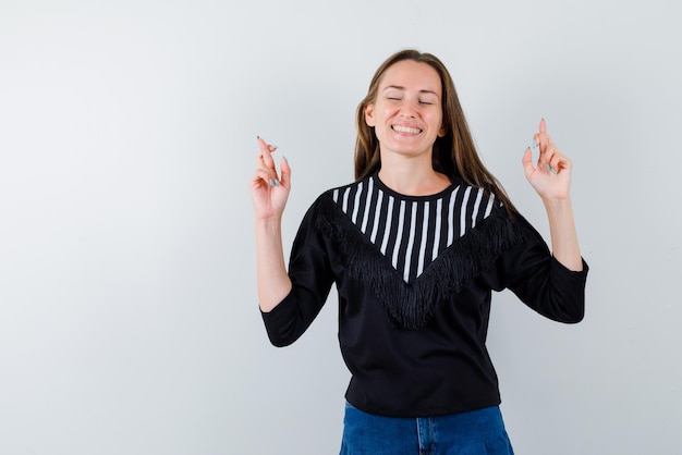 Mulher jovem sorridente mostrando um gesto de mão de boa sorte no fundo branco