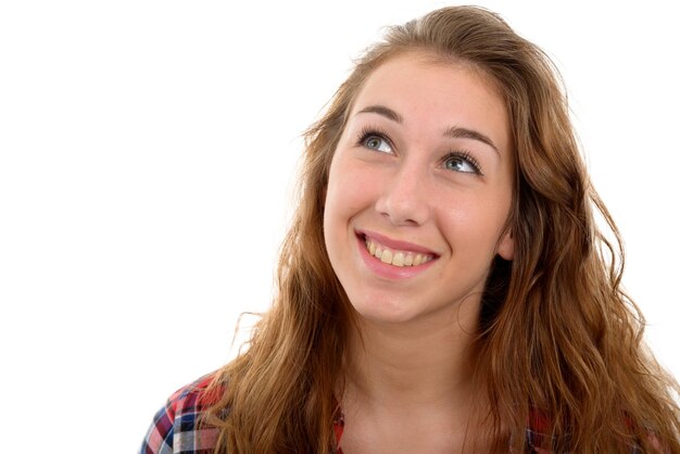 Mulher jovem sorridente olhando para longe contra um fundo branco