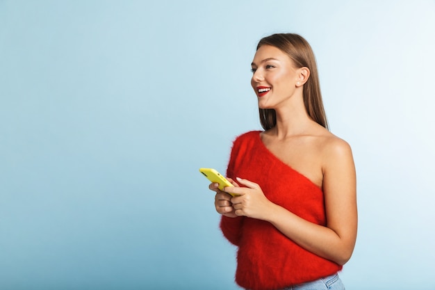 Foto mulher jovem sorridente posando isolada, usando telefone celular.