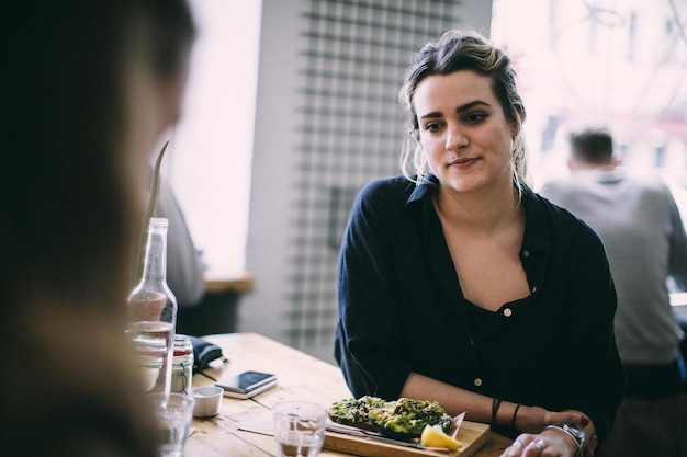 Mulher jovem sorridente sentada na mesa no restaurante