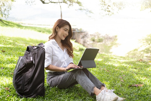 Mulher jovem sorridente usando laptop no parque