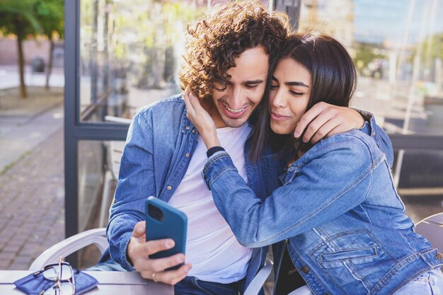 Foto mulher jovem sorridente usando telefone celular enquanto está sentada ao ar livre