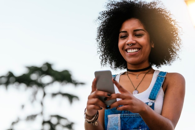 Foto mulher jovem sorridente usando telefone móvel contra o céu