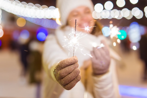 Mulher jovem sorridente, vestindo roupas de malha de inverno, segurando o diamante ao ar livre sobre fundo de neve. Férias de natal.