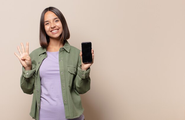 Mulher jovem sorrindo e parecendo amigável, mostrando o número quatro ou o quarto com a mão para a frente, em contagem regressiva