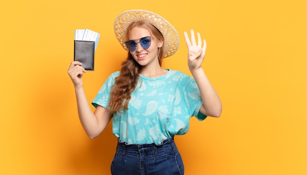 Mulher jovem sorrindo e parecendo amigável, mostrando o número quatro ou o quarto com a mão para a frente, em contagem regressiva