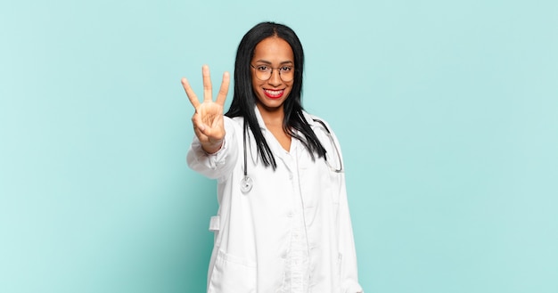 Mulher jovem sorrindo e parecendo amigável, mostrando o número três ou o terceiro com a mão para a frente, em contagem regressiva