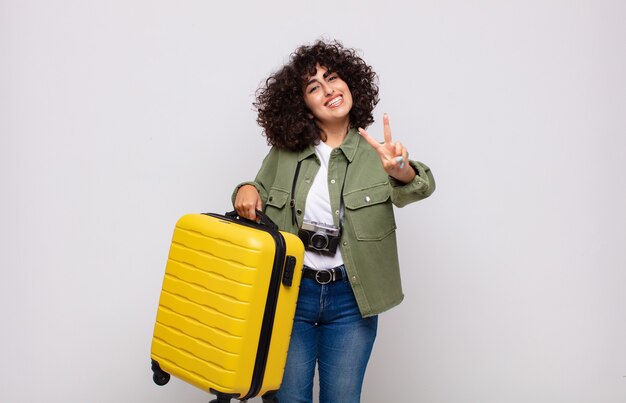 Mulher jovem sorrindo e parecendo feliz, despreocupada e positiva, gesticulando vitória ou paz com uma mão