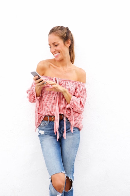 Mulher jovem sorrindo e segurando um telefone celular contra um fundo branco isolado