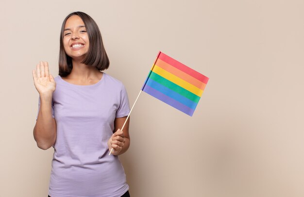 Mulher jovem sorrindo feliz e alegremente, acenando com a mão, dando as boas-vindas e cumprimentando você ou dizendo adeus