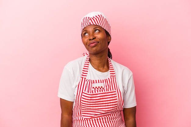 Mulher jovem sorveteira afro-americana isolada em um fundo rosa sonhando em alcançar objetivos e propósitos