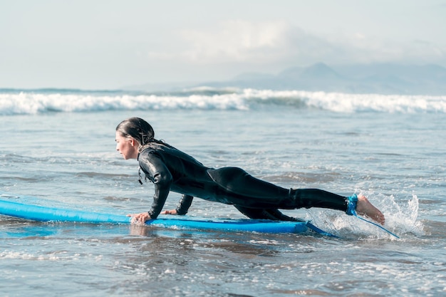 Mulher jovem surfista sobre uma prancha de surf na água