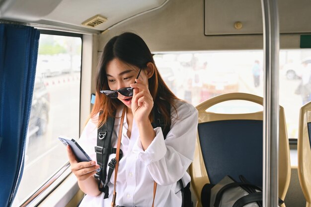 Foto mulher jovem surpreendida lendo mensagem em seu telefone celular enquanto viajava de ônibus