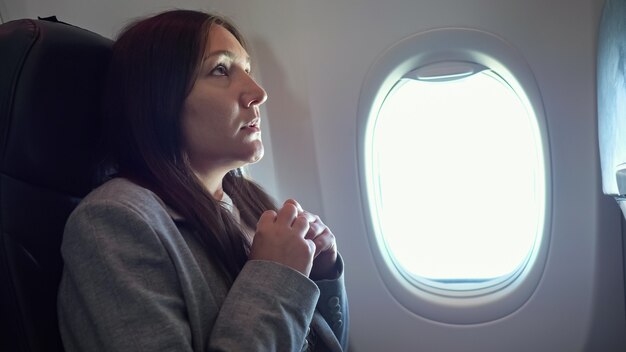 Mulher jovem tem muito medo de voar em um avião.