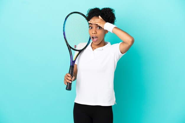 Mulher jovem tenista isolada em um fundo azul fazendo gesto de surpresa enquanto olha para o lado