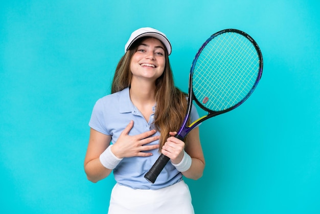 Mulher jovem tenista isolada em um fundo azul sorrindo muito