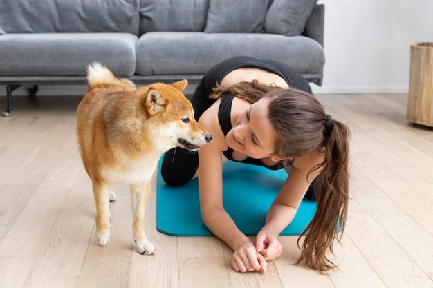 Foto mulher jovem tentando praticar esportes em casa com o cachorro