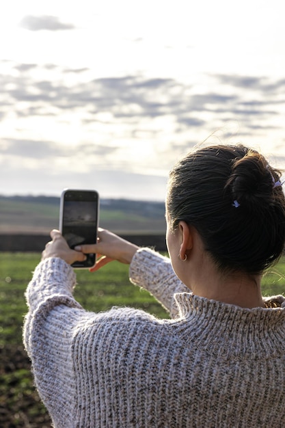 Mulher jovem tira foto do campo pelo smartphone