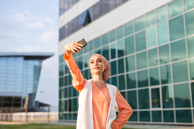 Foto mulher jovem tirando uma selfie enquanto estava de pé contra o prédio