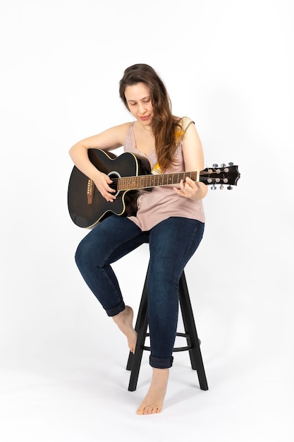 Mulher jovem tocando guitarra em fundo branco