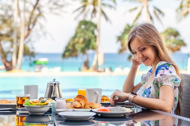 Mulher jovem tomando café da manhã em resort restaurante piscina turquesa fundo do mar