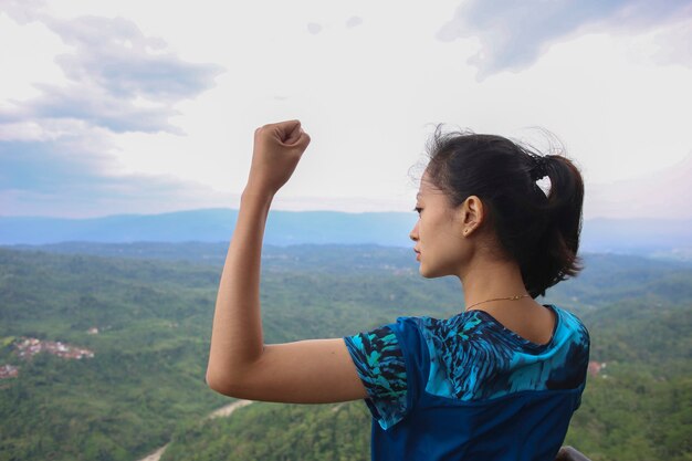 Mulher jovem torcendo de braços abertos no pico da montanha