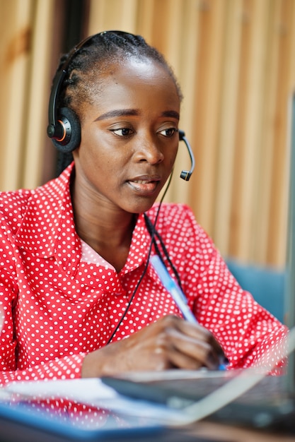 Mulher jovem trabalha em uma operadora de call center e agente de atendimento ao cliente usando fones de ouvido e um laptop.
