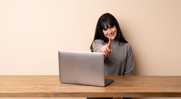 Mulher jovem, trabalhando, com, dela, laptop, mostrando, e, levantamento, um, dedo