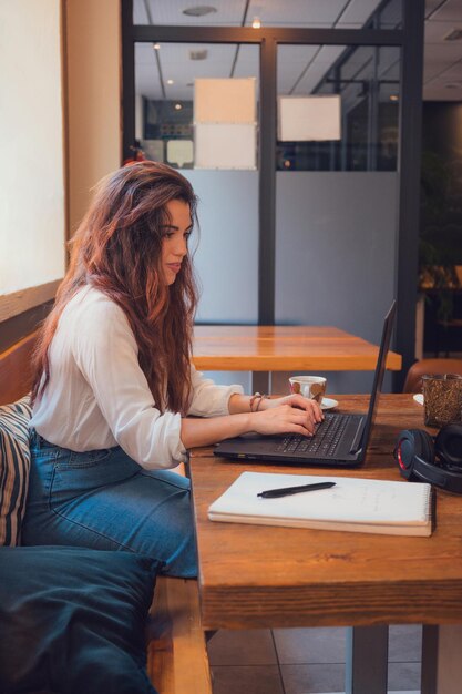 Mulher jovem trabalhando em um restaurante com seu laptop