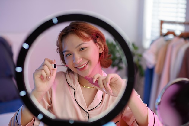 Mulher jovem transgênero sorridente filmando blog de beleza aplicando maquiagem