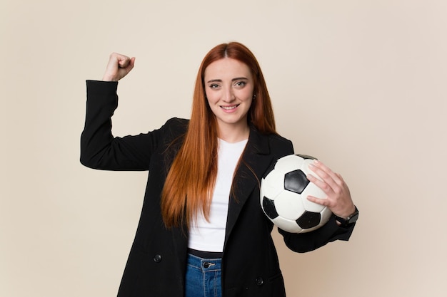 Mulher jovem treinador de futebol segurando uma bola de futebol isolada