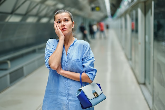 Mulher jovem triste com bolsa na estação de metrô