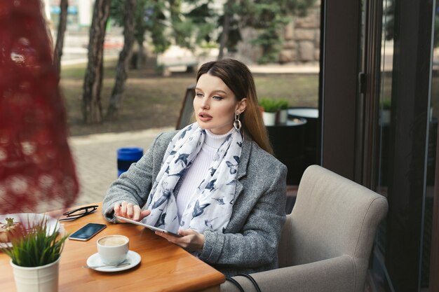 Mulher jovem triste com um tablet em um café