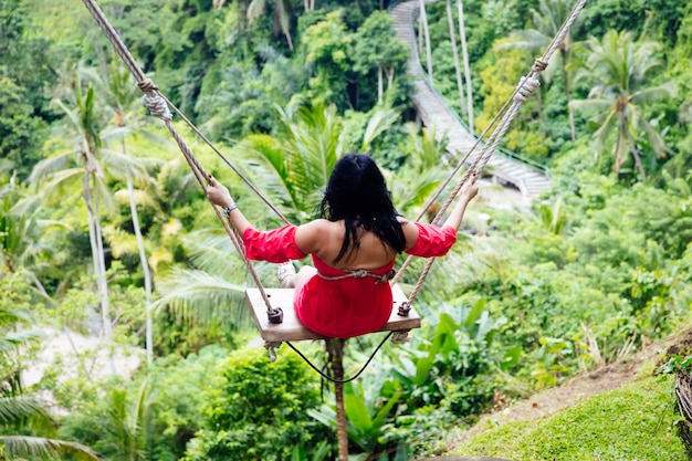 Mulher jovem turista balançando sobre a floresta tropical na ilha de bali