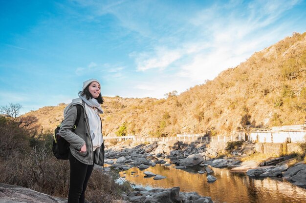 Mulher jovem turista caucasiana em pé nas margens de um rio