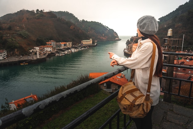 Mulher jovem turista caucasiana, olhando para a baía de um ponto de vista elevado em Pasaia; País Basco.