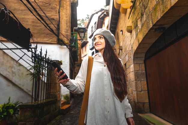 Mulher jovem turista caucasiana usando o smartphone em uma cidade velha.