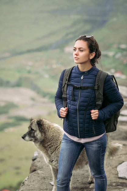 Mulher jovem turista com uma mochila no contexto das montanhas do cáucaso, geórgia em um dia de neblina