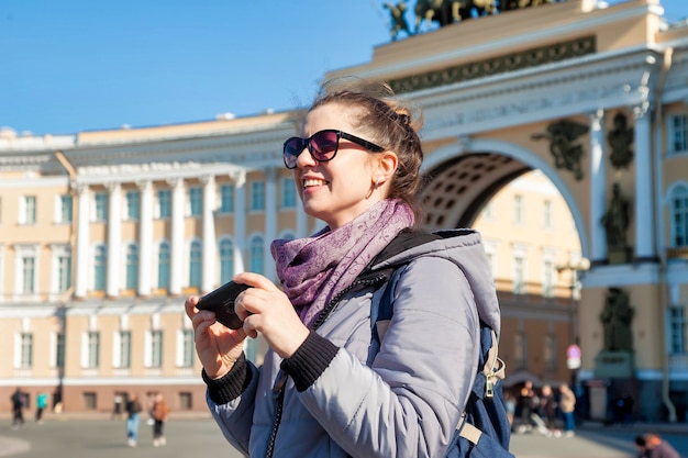 Mulher jovem turista de retrato com telefone, levanta e tira fotos de pontos turísticos de São Petersburgo. Conceito de viagens incríveis e aventuras inesquecíveis. Copie o espaço