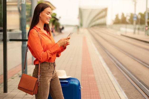 Mulher jovem turista enviando mensagens no celular na estação de bonde