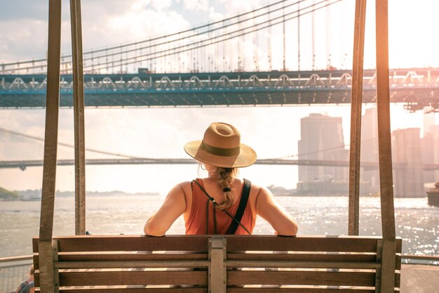 Mulher jovem turista na ponte do Brooklyn e na ponte de Manhattan. Viajante solo da cidade de Nova York nos EUA.