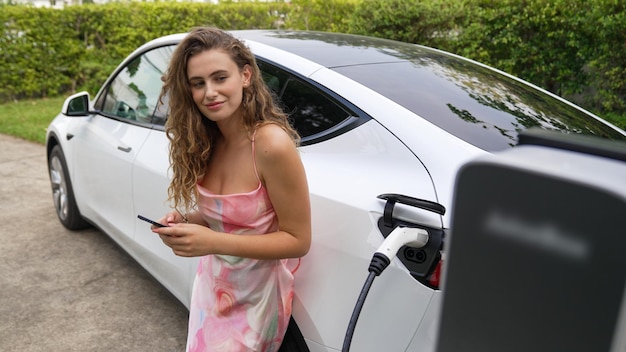 Foto mulher jovem usa smartphone para pagar eletricidade para carro elétrico synchronos