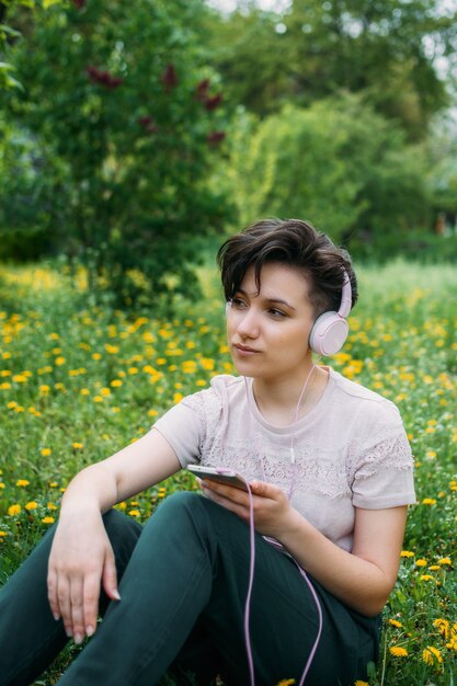 Mulher jovem usando fones de ouvido e smartphone usando o aplicativo de rede social de bate-papo com áudio, ouvindo voz