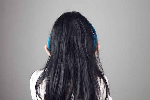 Mulher jovem usando fones de ouvido grandes em um fundo cinza