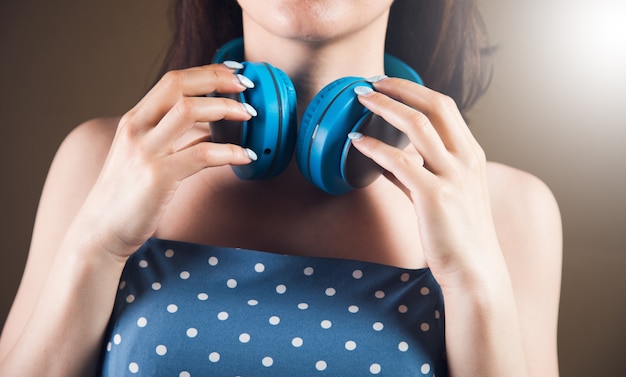 Mulher jovem usando fones de ouvido grandes em um fundo marrom