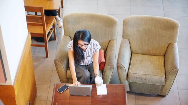 Mulher jovem usando laptop e smartphone no café