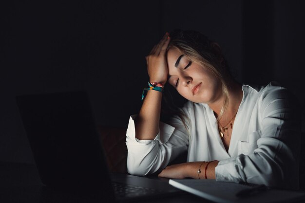 Foto mulher jovem usando laptop enquanto está sentada na mesa