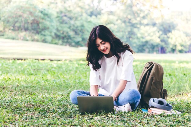 Mulher jovem usando laptop enquanto está sentada no campo